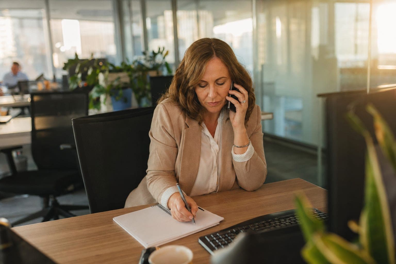 Recruiterin im Telefonat mit Notizblock am Schreibtisch